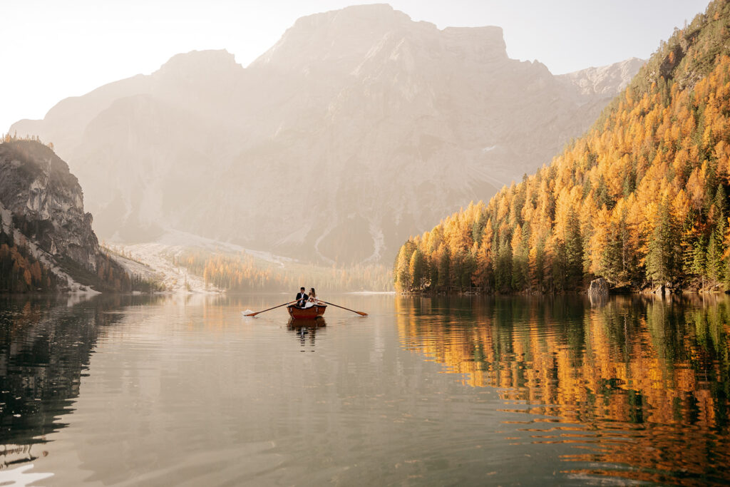 Couple rowing on serene mountain lake at sunrise.