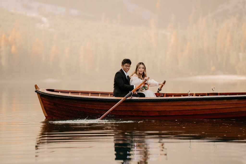 Couple rowing in wooden boat on serene lake.