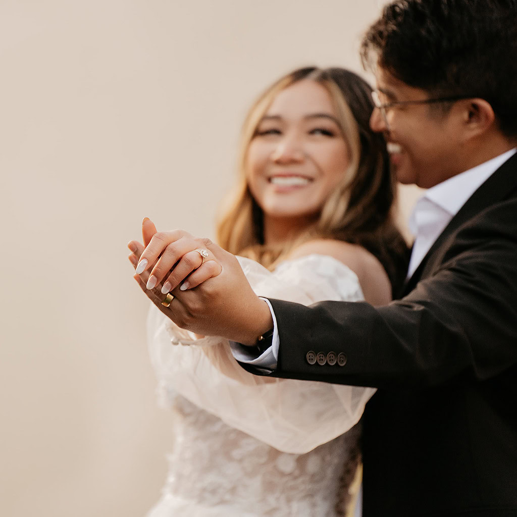 Couple smiling and holding hands at wedding.