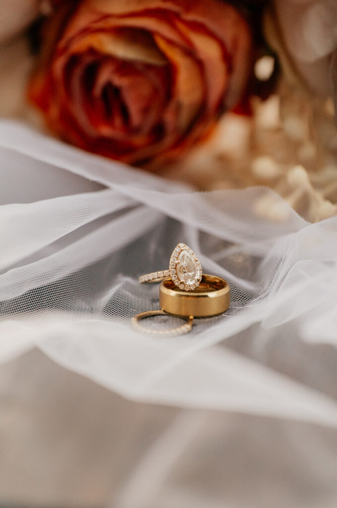 Gold wedding rings on white fabric with rose.