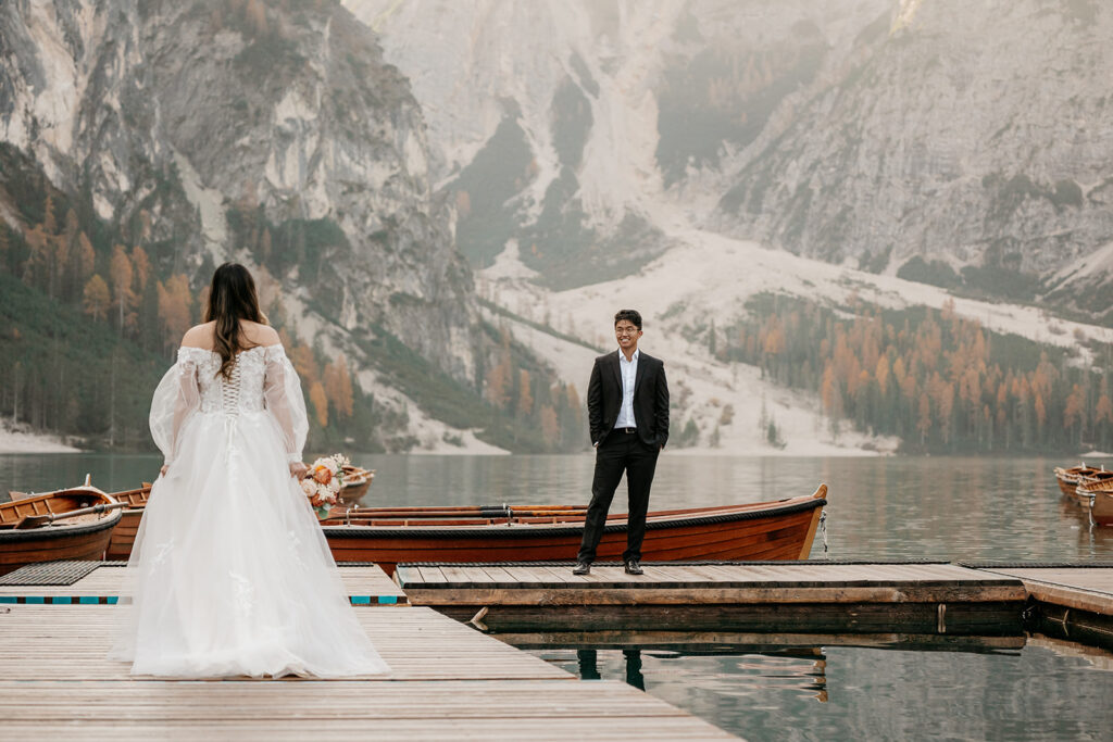 Bride and groom on lake dock with mountains