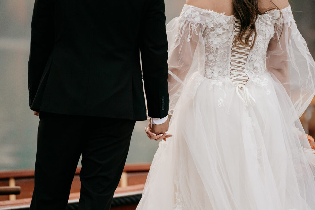 Bride and groom holding hands, elegant wedding clothes.