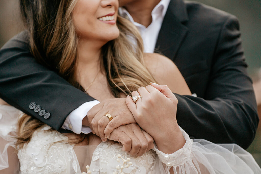 Close-up of couple holding hands, showing wedding rings.