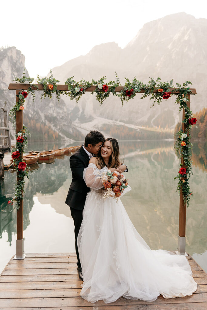 Couple embraces at lakeside wedding ceremony.