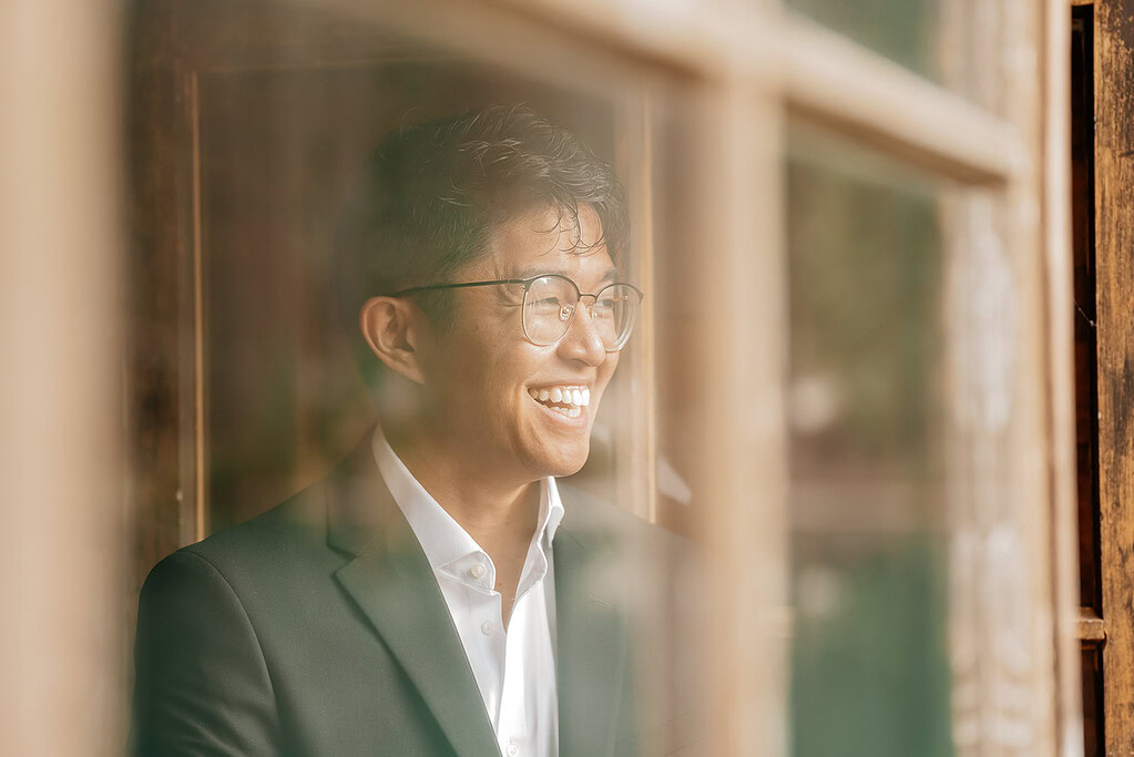 Smiling person in suit behind window.