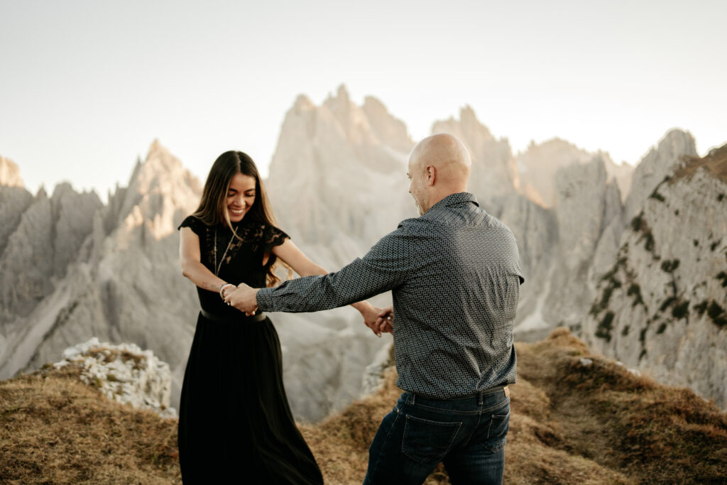 Couple dancing on mountain summit at sunset.