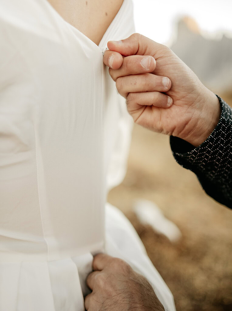 Person fastening white dress back button