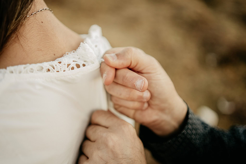 Hand adjusting white lace dress on shoulder