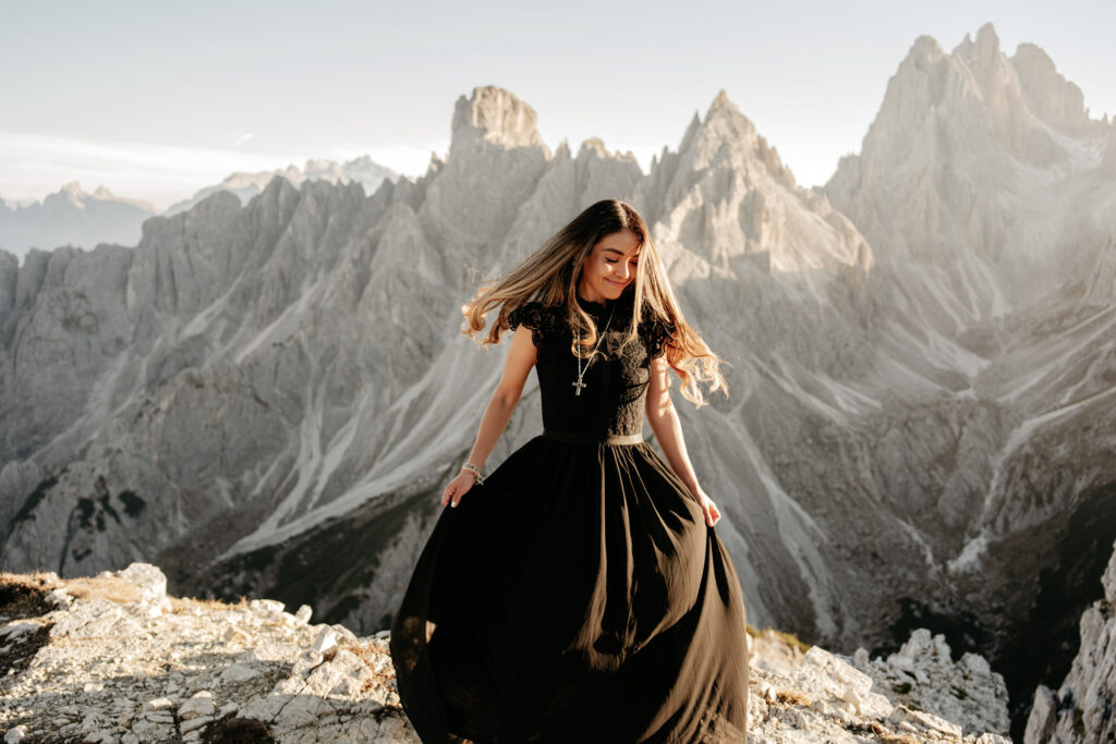 Woman in black dress, mountain landscape background.