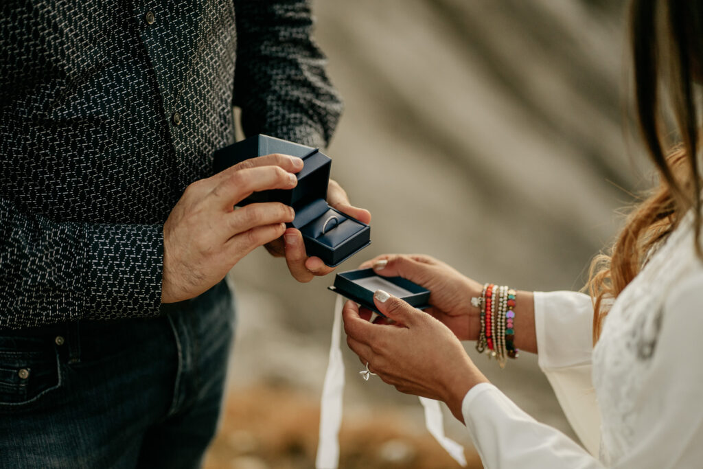 Couple exchanging wedding rings in blue boxes.