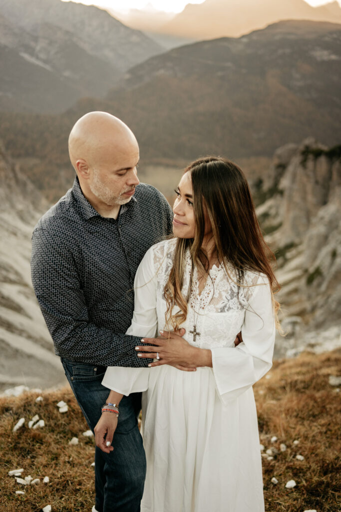 Couple embracing on mountain landscape at sunset.