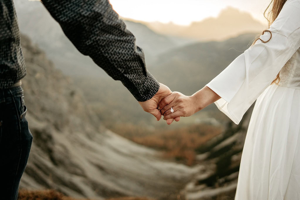 Couple holding hands in a scenic mountain view.