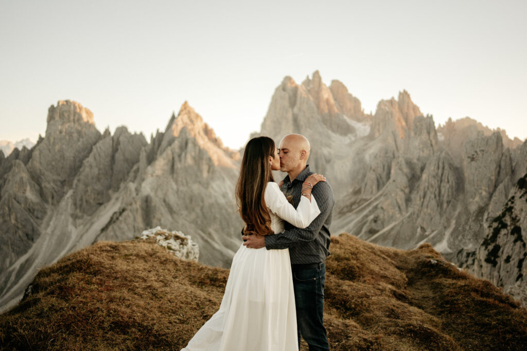 Couple kissing in mountain landscape at sunset.