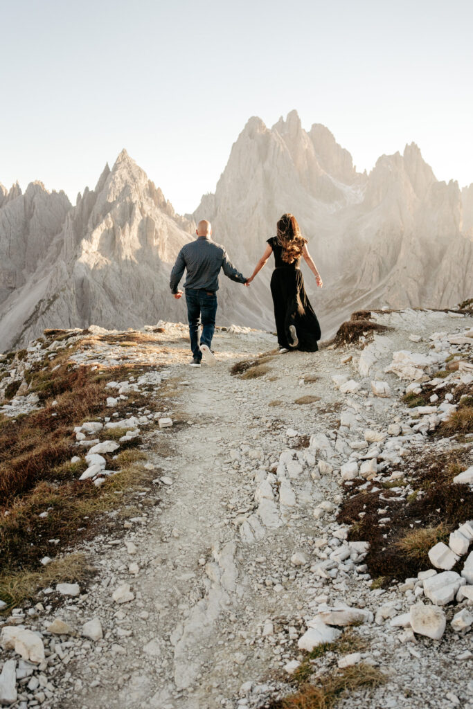 Couple hiking in mountainous landscape at sunrise.