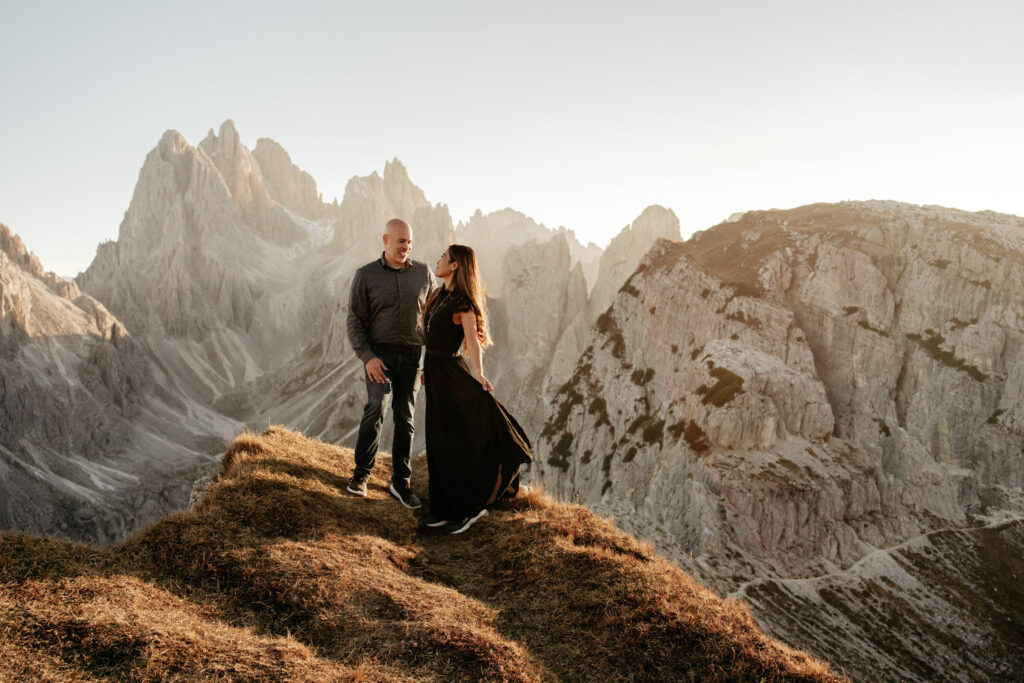 Couple standing on mountain cliff at sunrise.