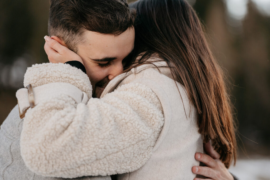 Couple hugging warmly in cozy jackets outdoors.