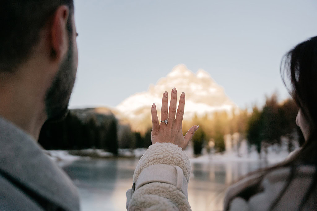 Engagement ring displayed in snowy mountain landscape.