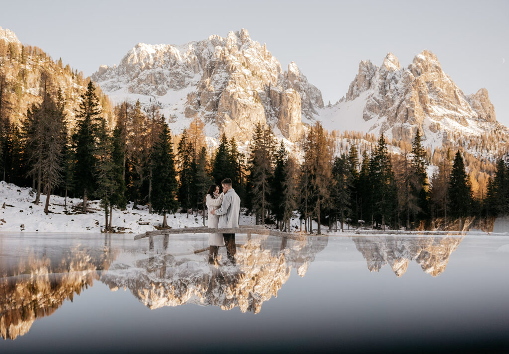 Couple embraced near snowy mountain lake reflection