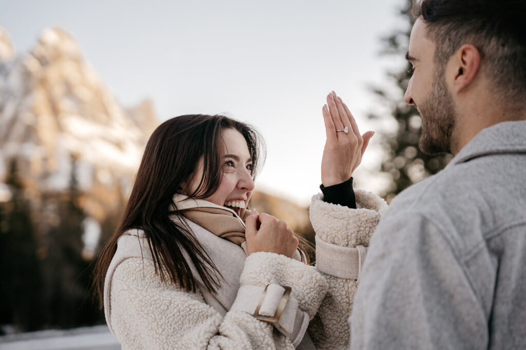 Couple celebrating engagement in snowy landscape.