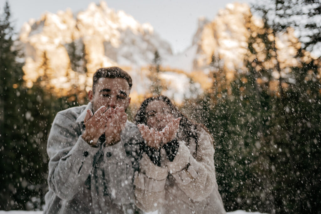 Couple playing with snow in a mountain landscape.