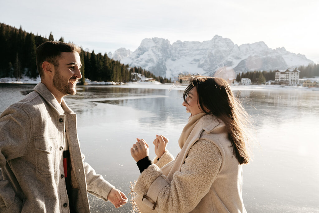 Couple laughing by snowy lake and mountains