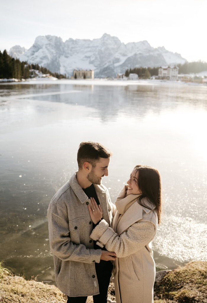 Couple smiling by a scenic lakeside mountain view.