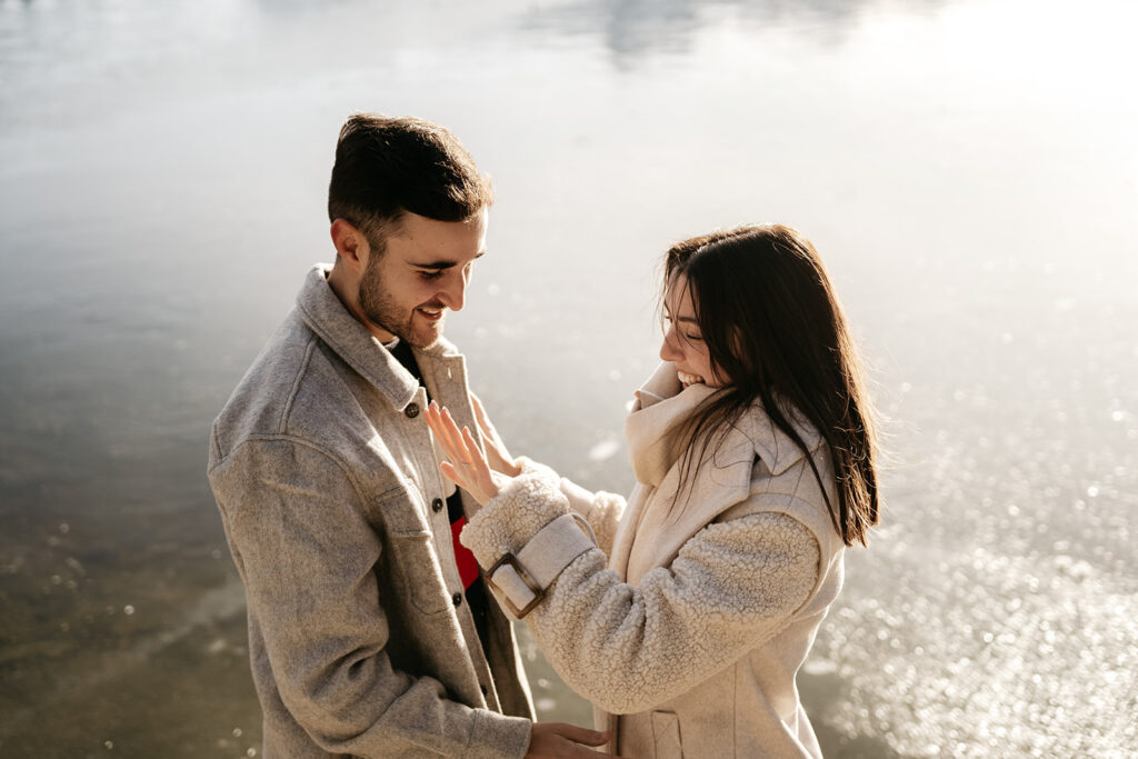 Couple smiling by a lake in winter coats