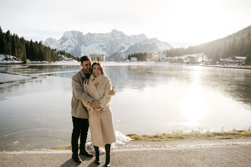 Couple embracing by mountain lake scenery in winter.