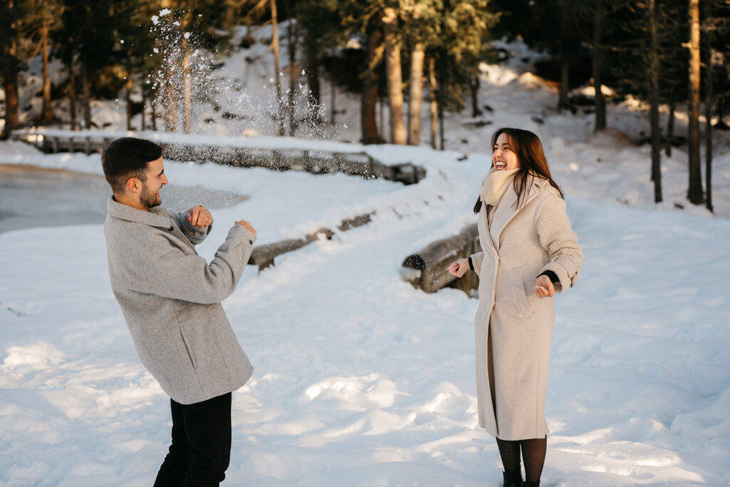 Couple enjoying snowball fight in snowy forest.