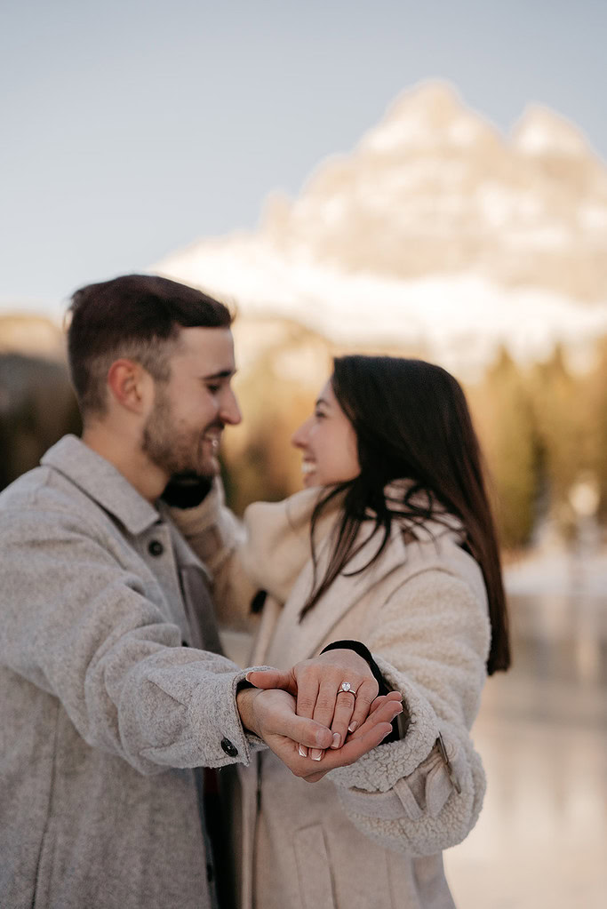 Couple showing engagement ring outdoors.