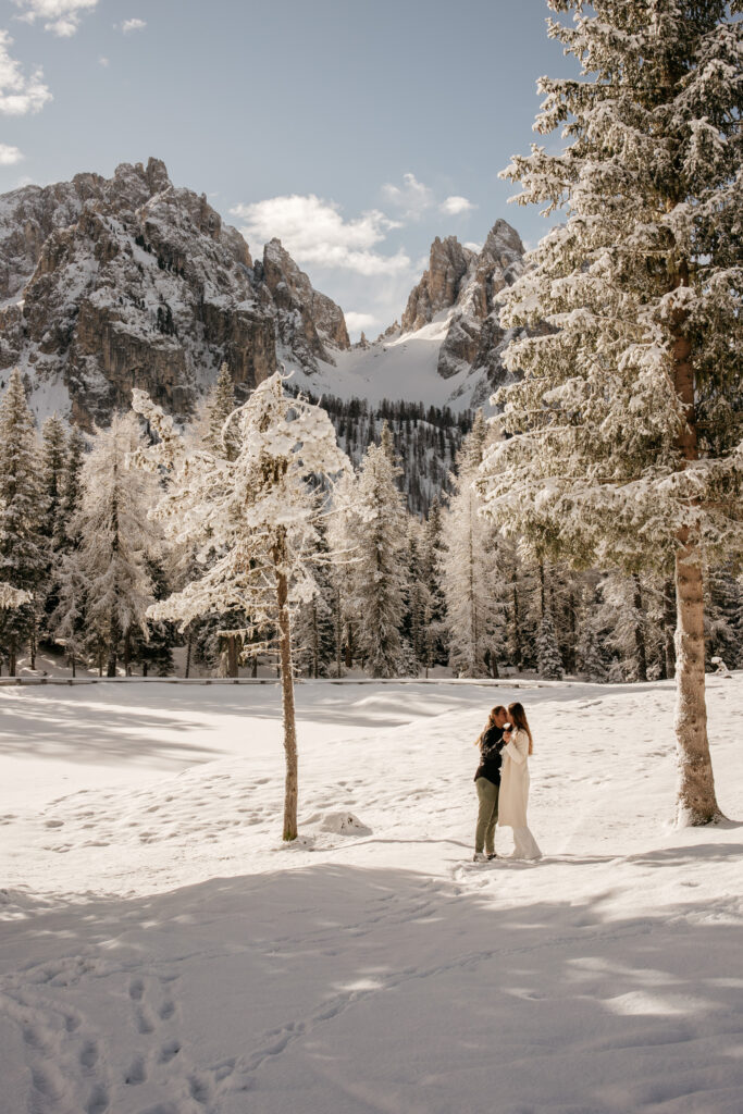 Couple embraces in snowy mountain landscape.