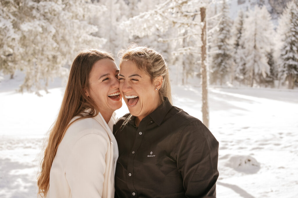 Two women laughing in snowy forest