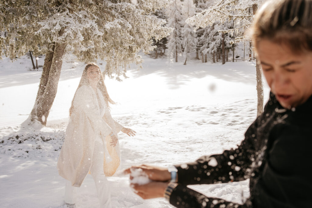 Two people having a snowball fight outdoors.