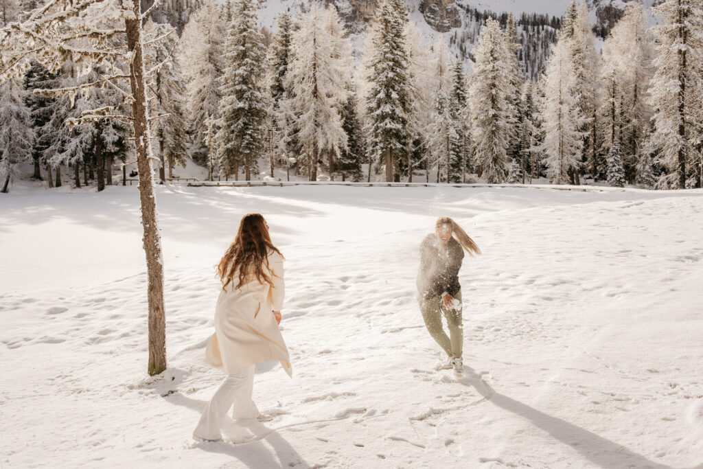 Two people having a snowball fight in forest.