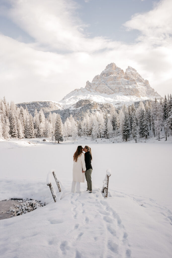 Couple kissing in snowy mountain landscape.