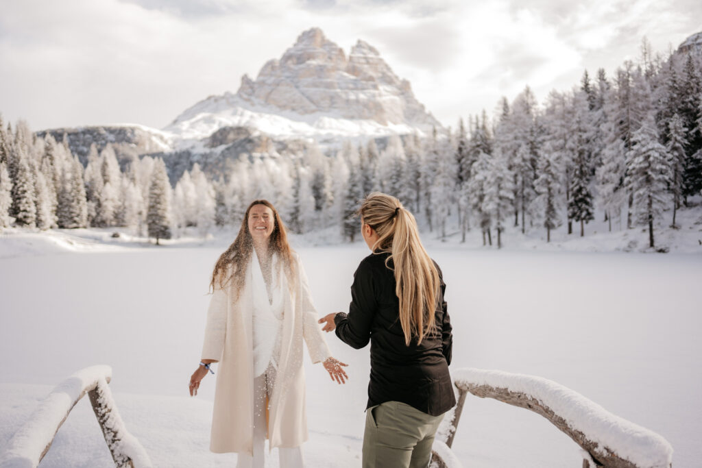 Two women enjoying snow in picturesque mountain landscape.