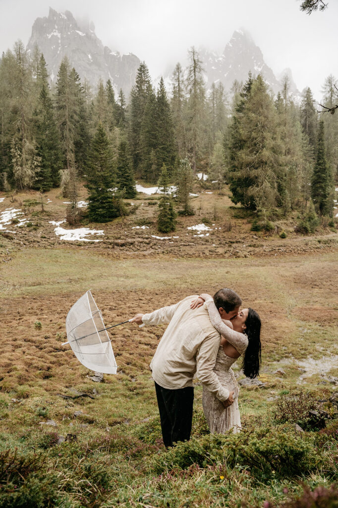 Couple kisses in misty mountain landscape