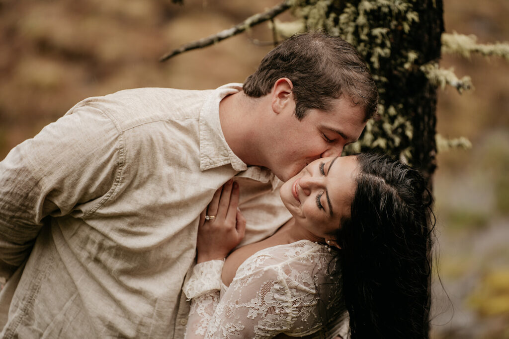 Couple embracing lovingly in a forest setting.