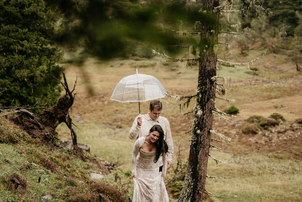 Couple hiking in forest with umbrella