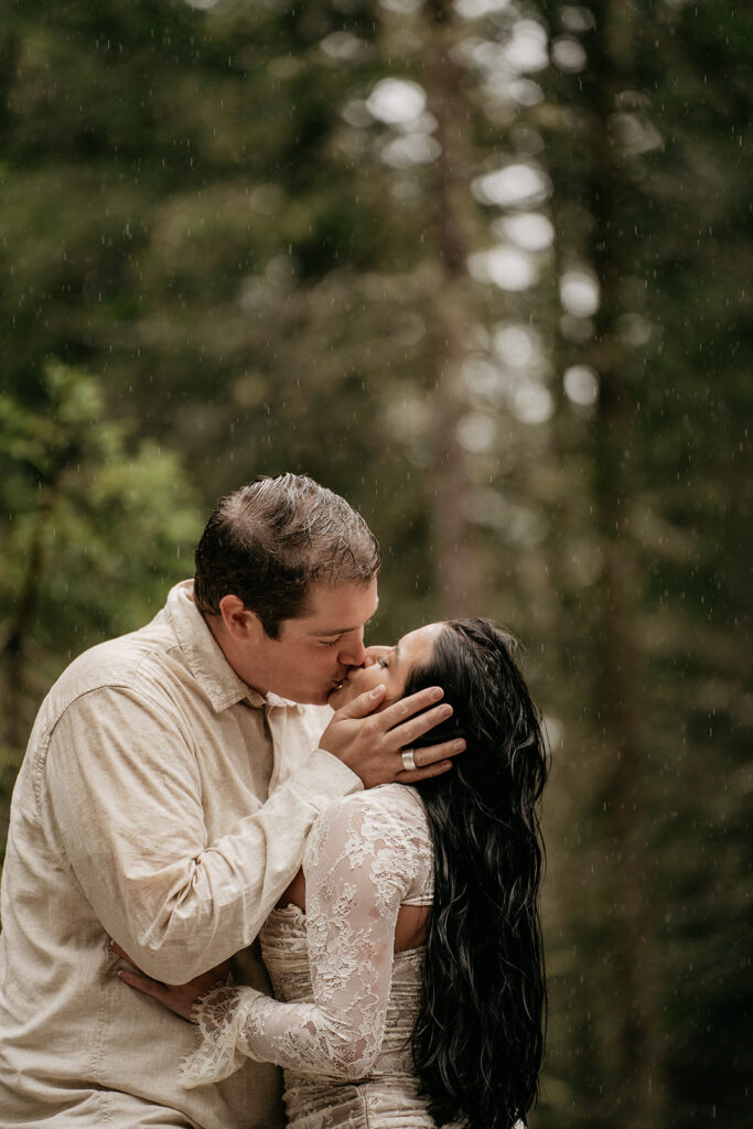 Couple kissing in the rain in forest.