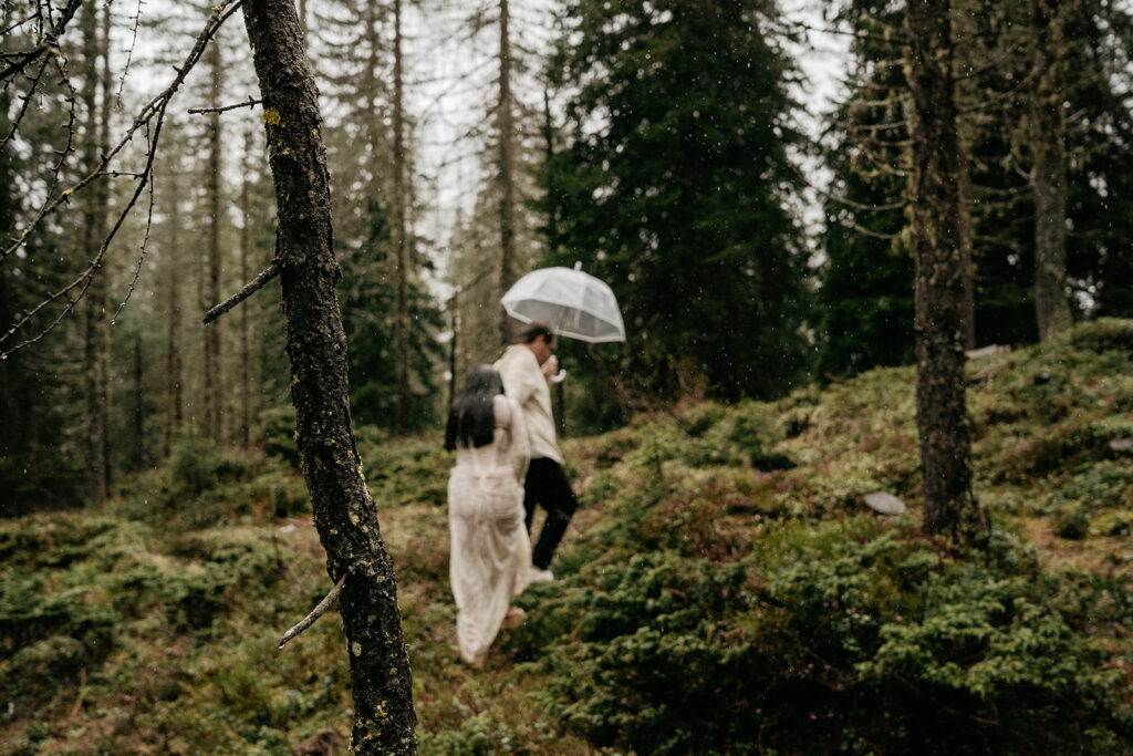 Couple walking in forest with umbrella.