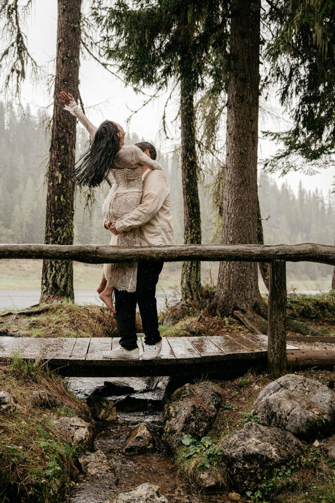 Couple embracing on bridge in forest rain