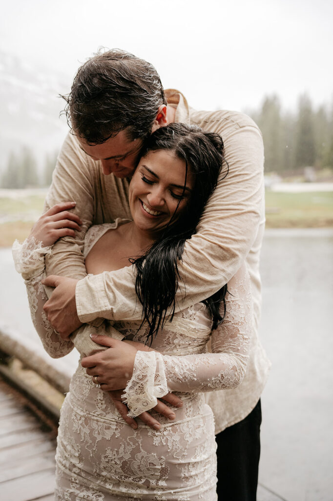 Couple embracing outdoors in rainy weather.