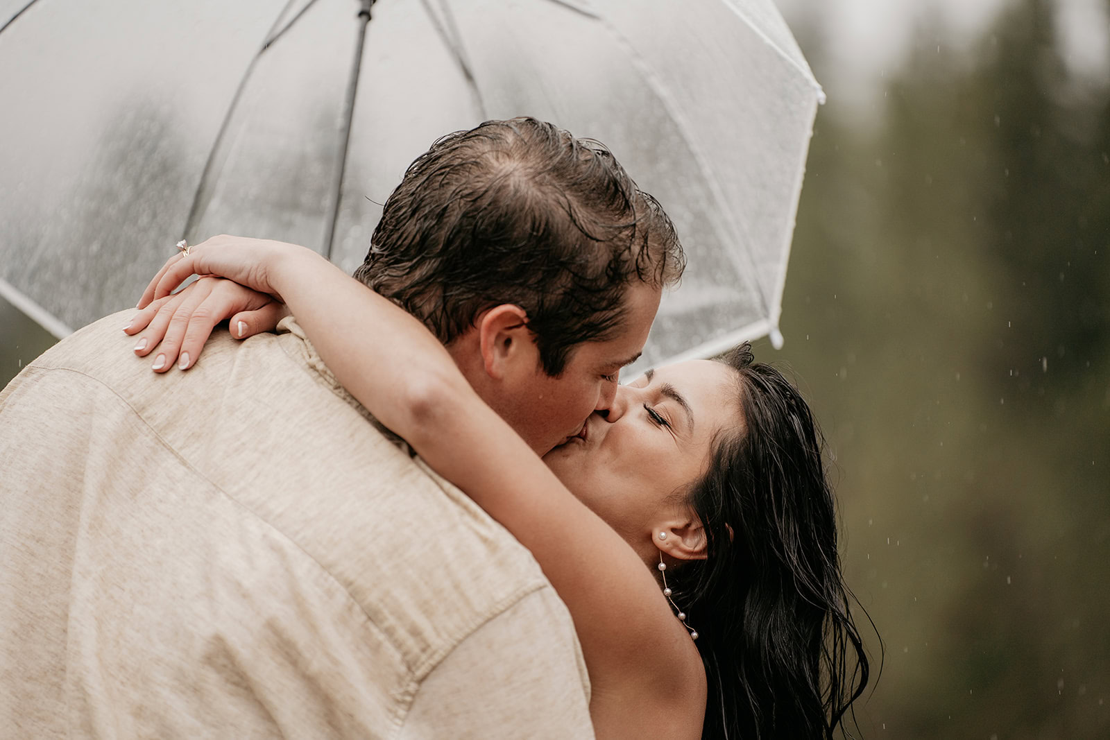 Couple kissing under an umbrella in the rain.