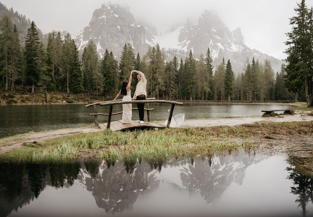 Couple dancing on lakeside wooden platform.