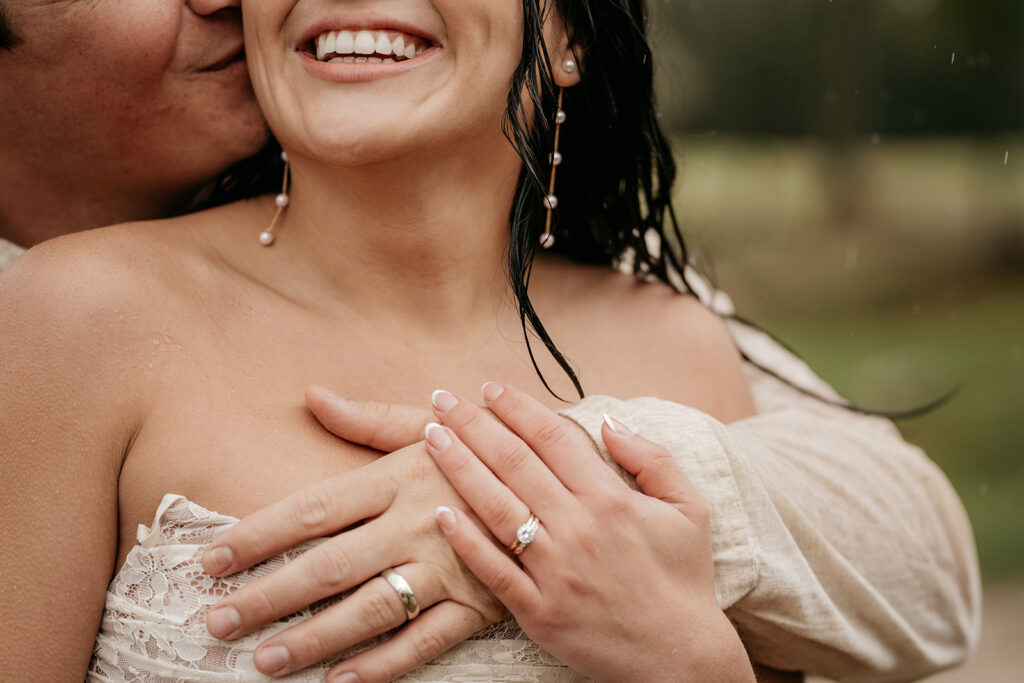 Couple embracing outdoors with smiles and rain drops.