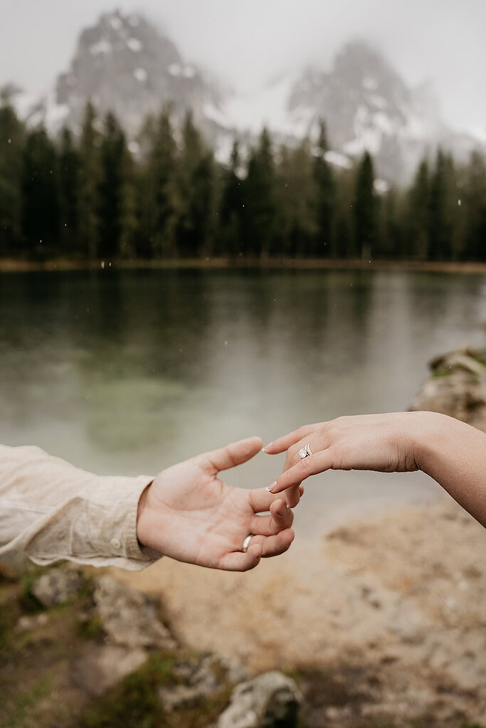 Hands reaching out near a serene lake