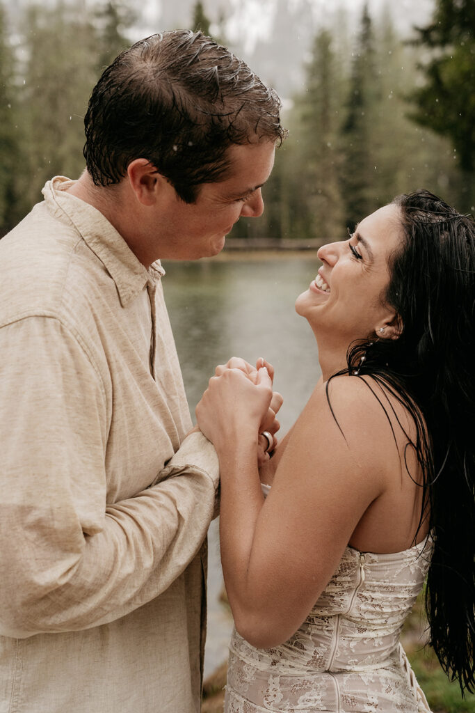 Couple smiling by a lake in rain