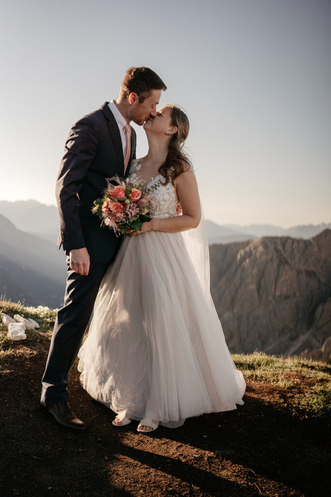 Bride and groom kissing on mountain top