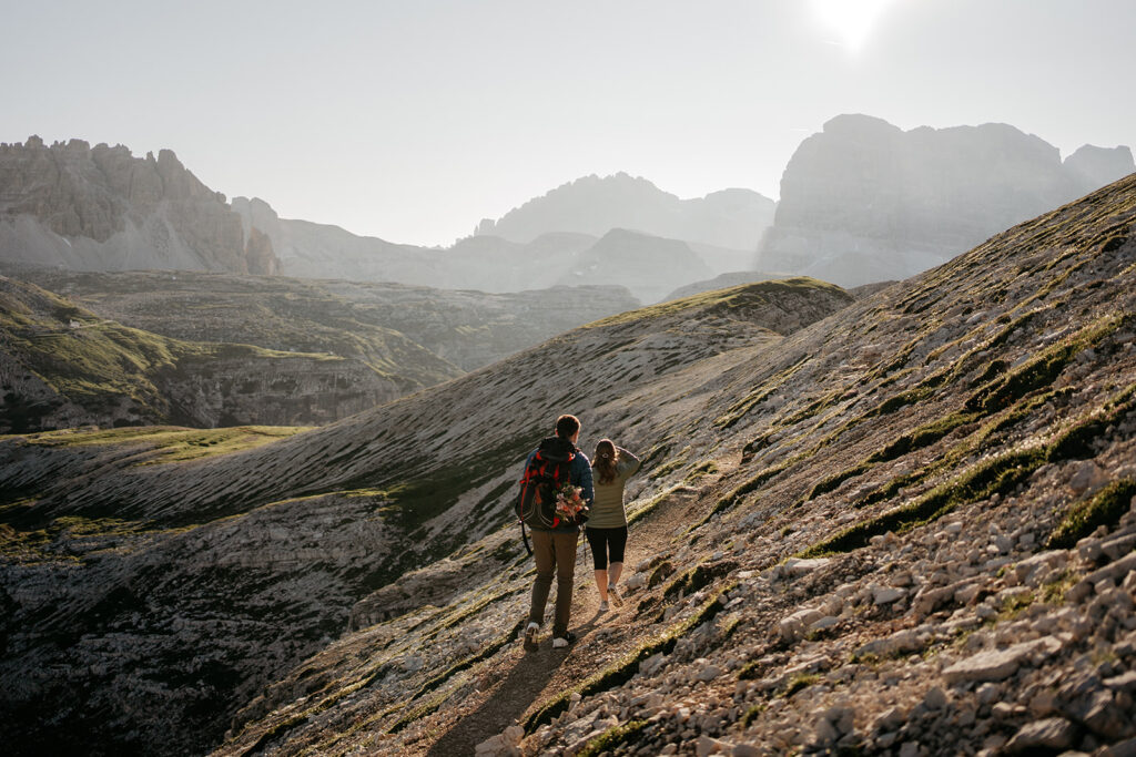 Couple hiking on mountain trail at sunrise.